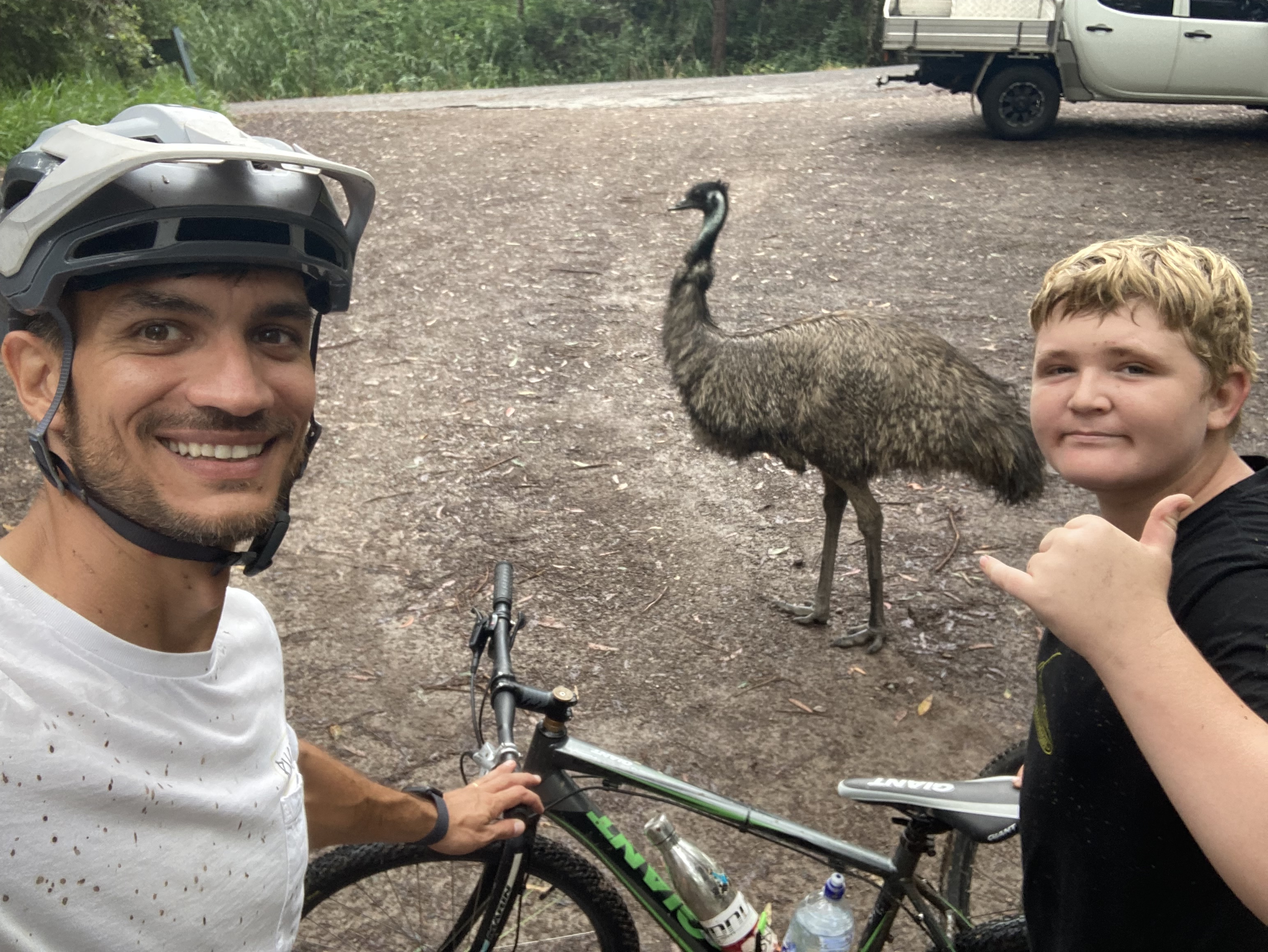 A support worker and a participant on a bike ride, stopped beside an emu